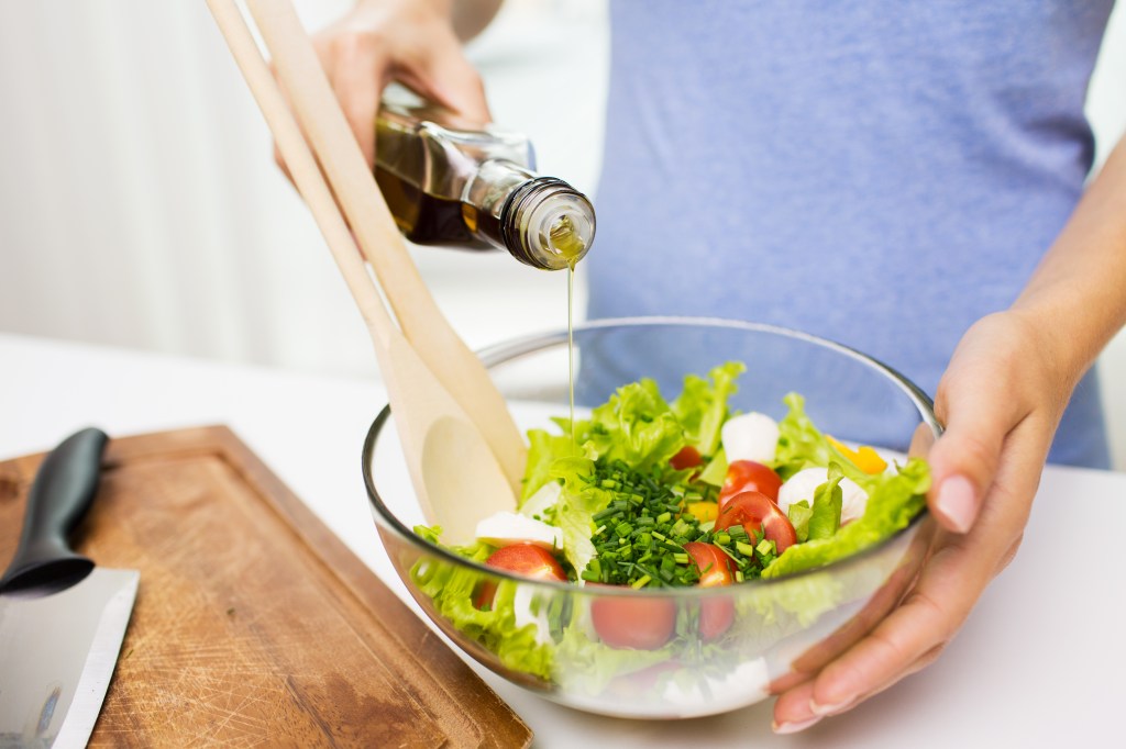 Pouring olive oil over salad
