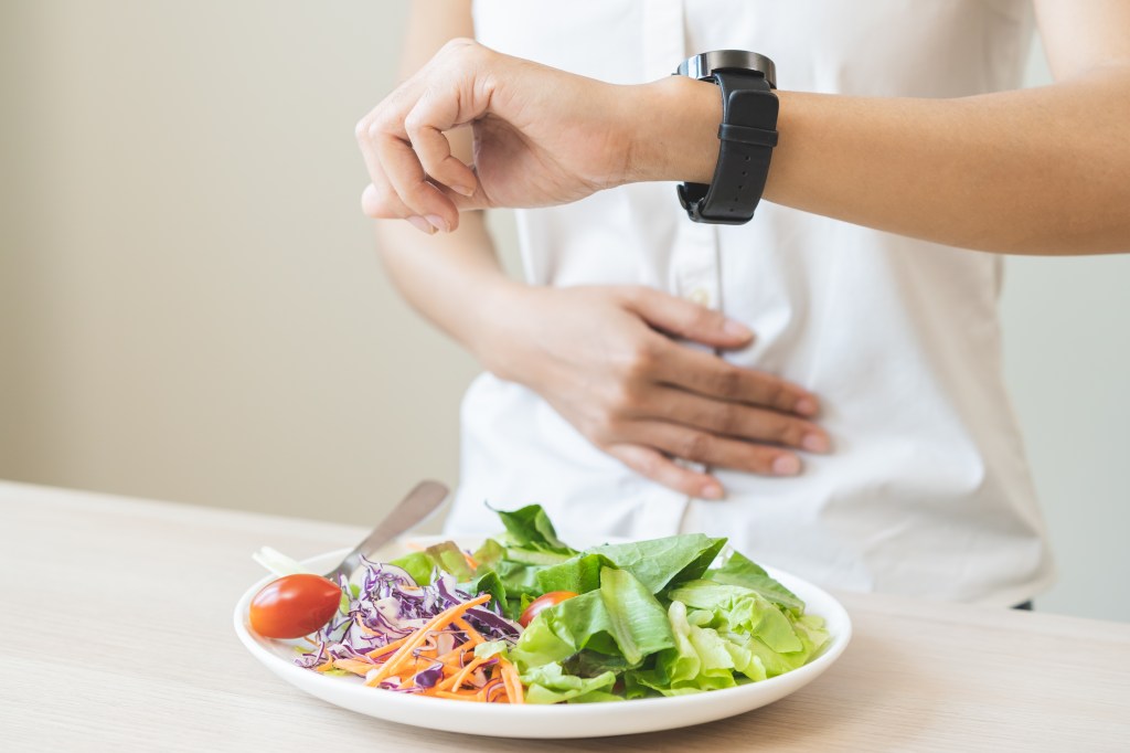 Woman with a plate of food and a clock