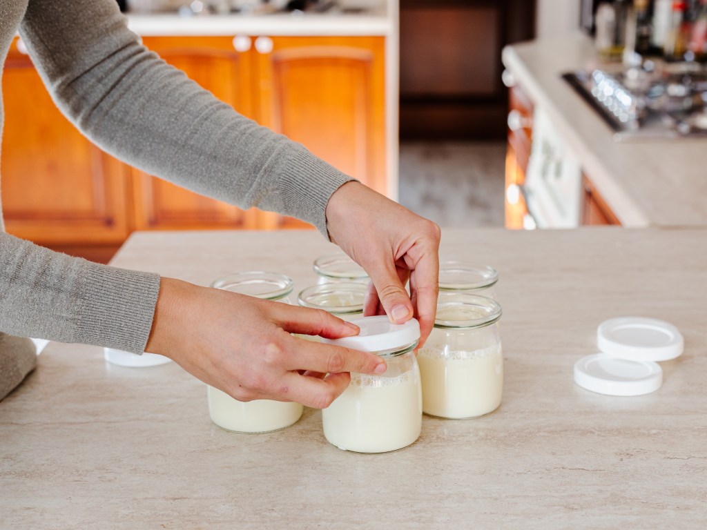 Person putting yogurt into a jar